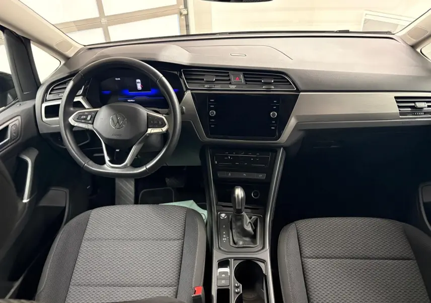 Intérieur avant du Volkswagen Touran 2024 avec tableau de bord moderne et volant multifonction noir.
