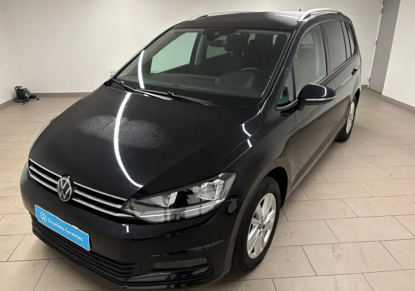 Volkswagen Touran 2024 noir intense nacré vu en 3/4 avant droit dans un intérieur lumineux.