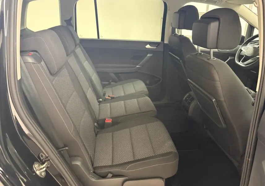 Vue intérieure côté gauche montrant les sièges arrière en tissu gris et l'avant du Volkswagen Touran noir intense nacré 2024.