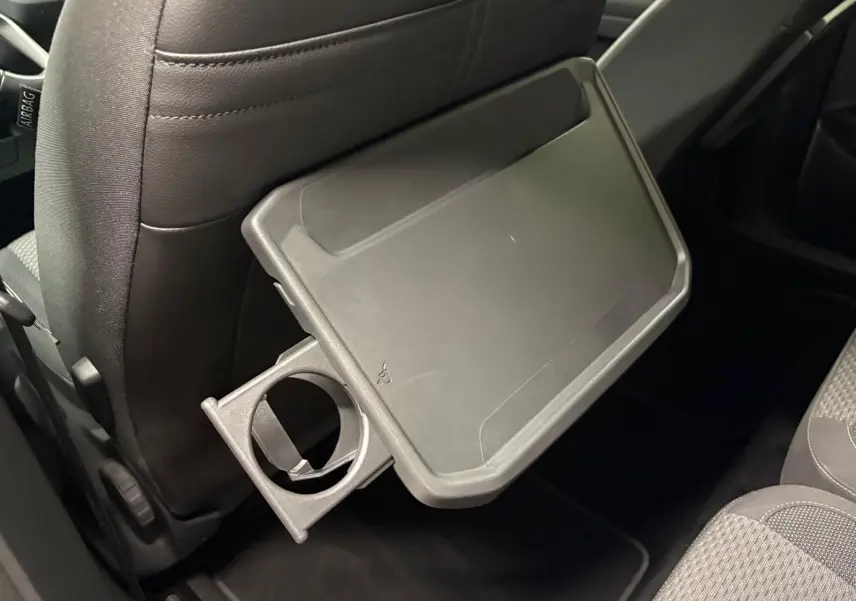 Tablette rabattable avec porte-gobelet intégrée au dos du siège avant dans l'habitacle du Volkswagen Touran noir intense nacré.