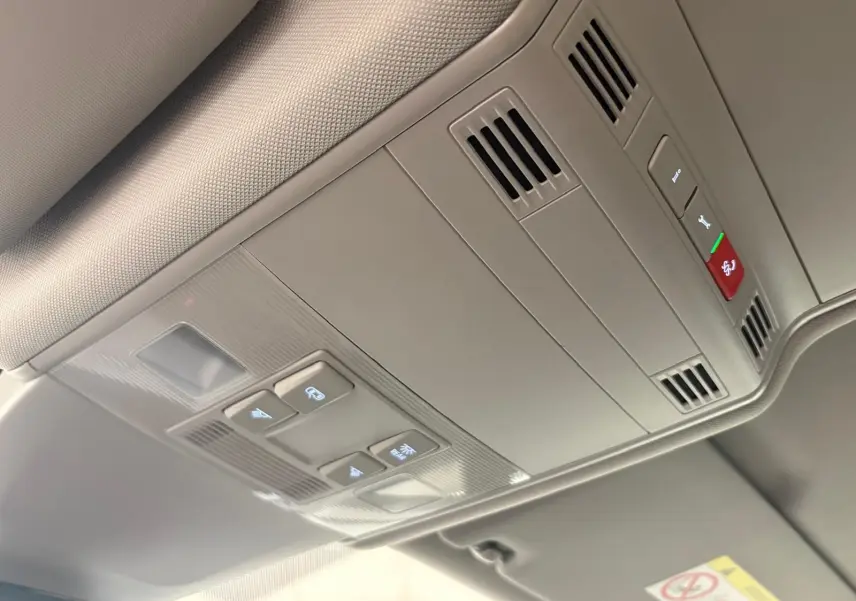 Plafonnier intérieur gris clair du Volkswagen Touran 2024 avec commandes d'éclairage et ventilation intégrées.