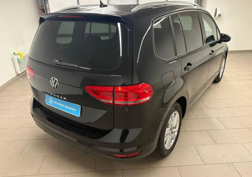 Vue 3/4 arrière droite du Volkswagen Touran noir intense nacré, soulignant son hayon électrique et vitres teintées.