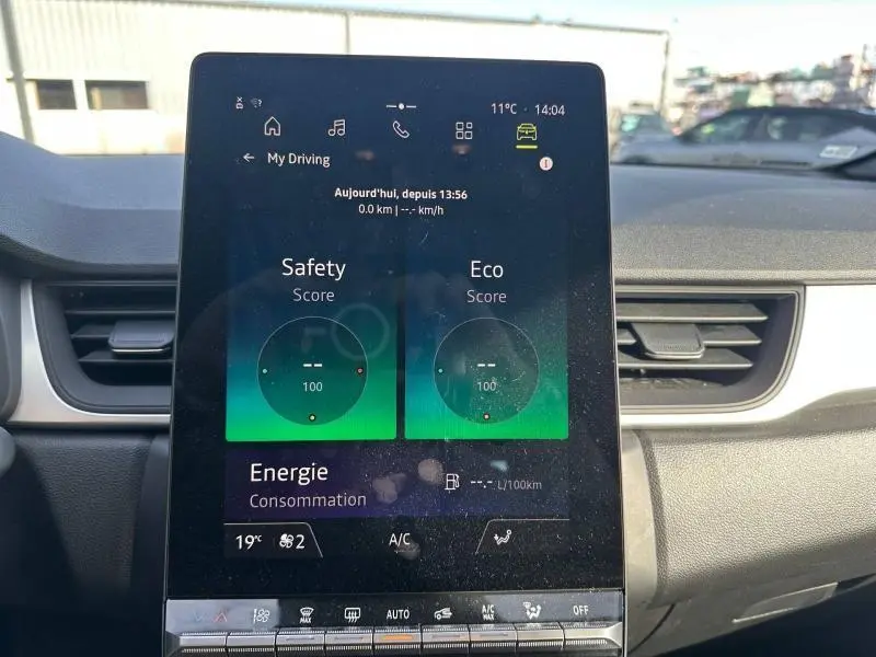 Écran tactile central du tableau de bord du Renault Captur blanc nacré/noir, affichant scores de conduite et consommation.