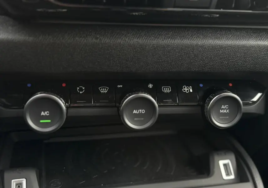 Détail de la console centrale avec commandes de climatisation automatique et recharge sans fil dans une Citroën C4 Hybrid gris Mercury.