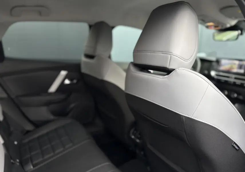 Vue intérieure arrière montrant les sièges bicolores gris clair et noir du Citroën C4 Hybrid 2025.