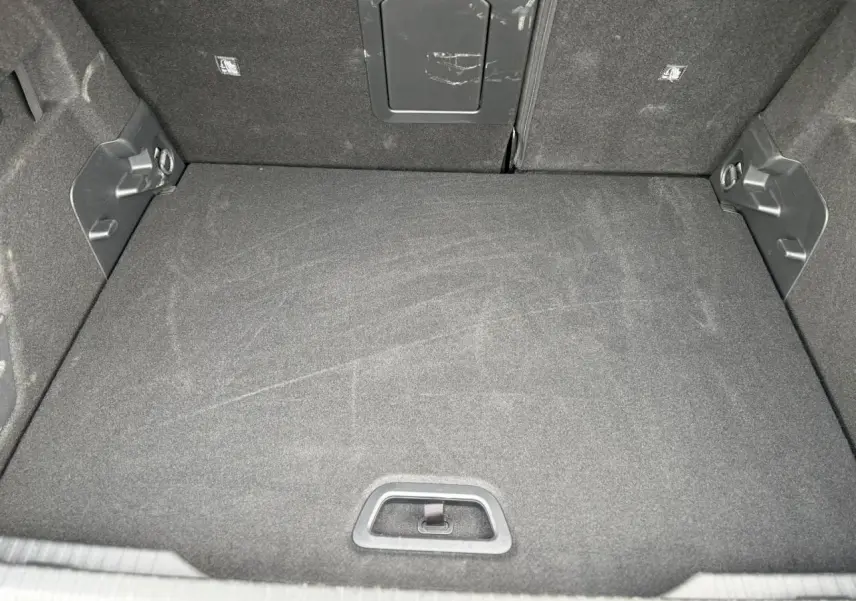 Vue intérieure du coffre spacieux et propre de la Citroën C4 Hybrid 145 gris Mercury, avec tapis de sol noir.