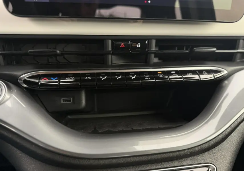 Vue rapprochée de la console centrale de la Fiat 500 électrique blanche, mettant en valeur les commandes de climatisation automatiques.