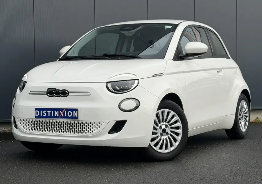 Vue 3/4 avant d'une Fiat 500 électrique blanche avec jantes multibranches et logo 500 noir sur calandre.