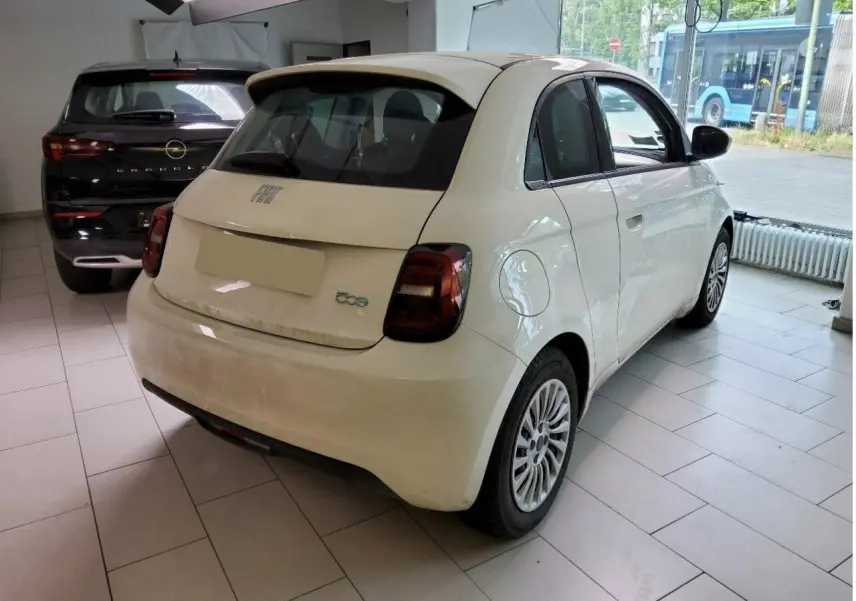 Vue intérieure côté droit de la Fiat 500 électrique 2024, sièges noirs avec surpiqûres blanches et tableau de bord moderne.