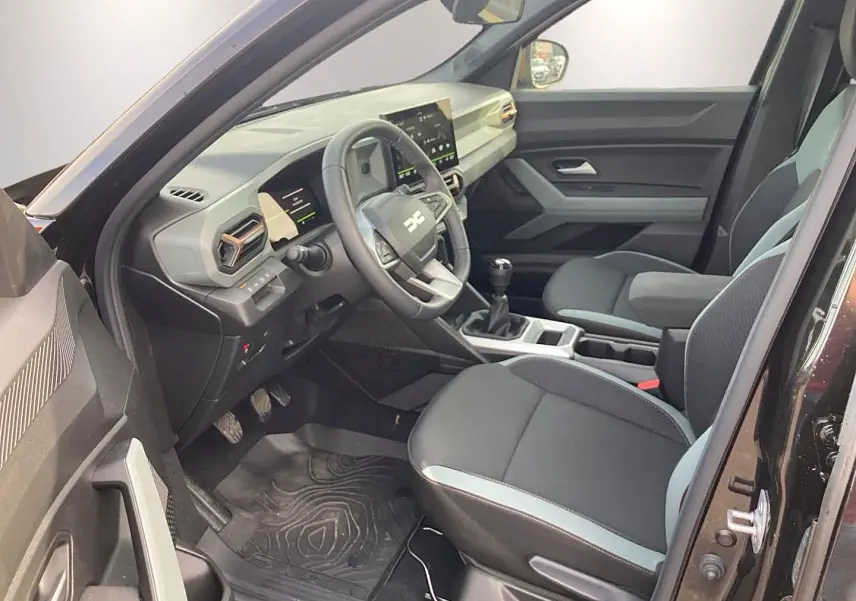 Vue intérieure côté conducteur du Dacia Bigster noir 2025, montrant le tableau de bord et les sièges avant.
