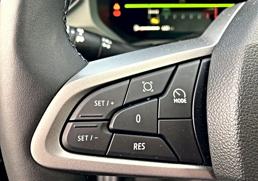 Gros plan sur les commandes multifonctions côté gauche du volant du Dacia Bigster noir, avec affichage numérique en arrière-plan.
