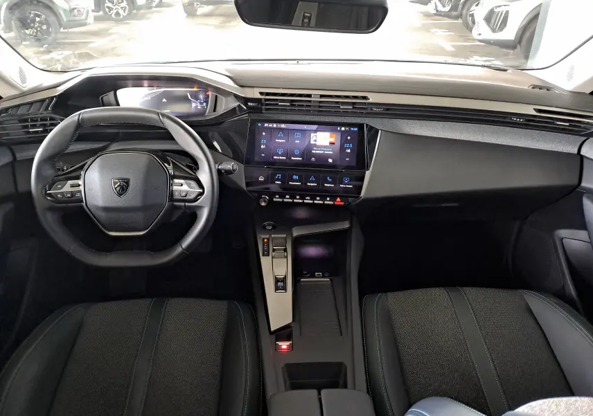 Intérieur noir de la Peugeot 308 2024, vue de face sur le tableau de bord et le volant compact au design moderne.