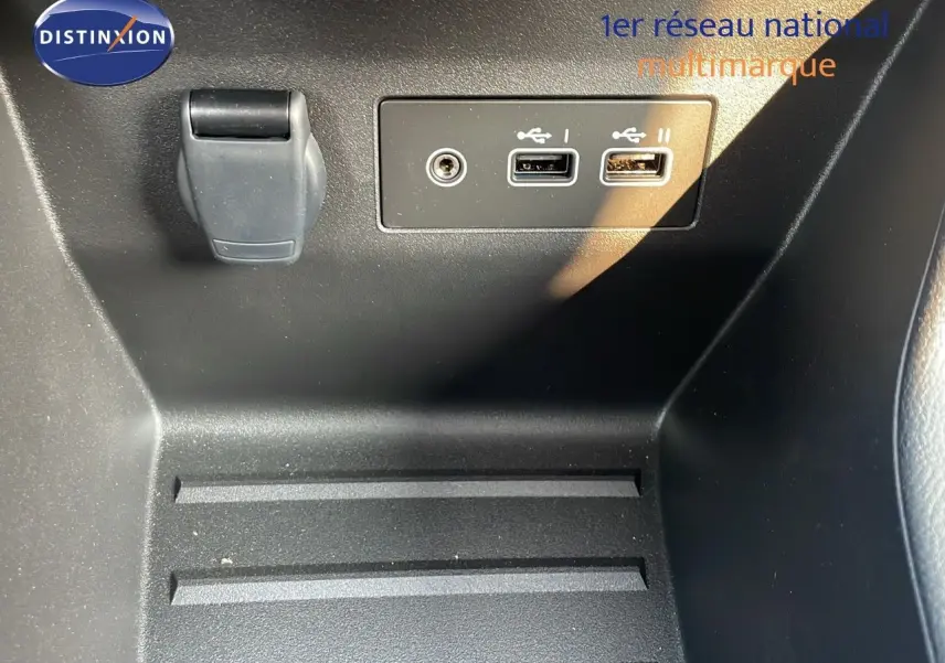 Prise USB double et prise jack dans l'habitacle noir d'une Renault Clio 1.5 dCi 2025, finition gris schiste métal.