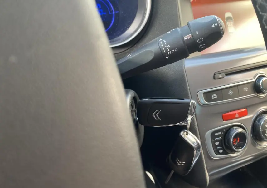 Gros plan intérieur sur la clé Citroën insérée dans le contact, avec tableau de bord et commandes de climatisation visibles.