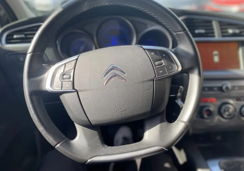 Volant en cuir noir de la Citroën C4 2017, avec commandes intégrées et tableau de bord flou en arrière-plan.