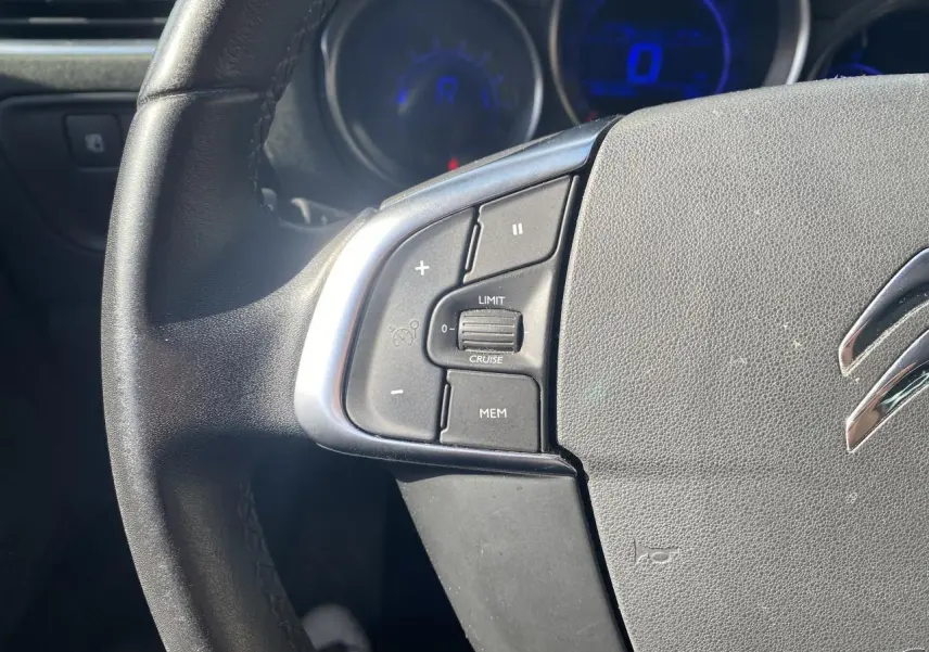 Gros plan sur le côté gauche du volant noir d'une Citroën C4 2017 avec commandes de régulateur de vitesse.