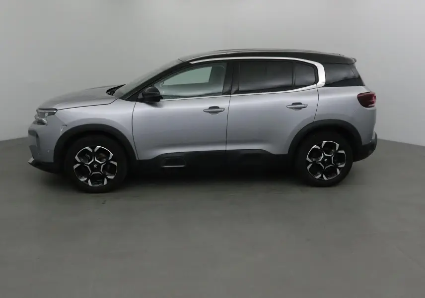 Profil côté gauche d'un Citroën C5 Aircross 2024 gris Artense avec toit noir et jantes alliage noires.