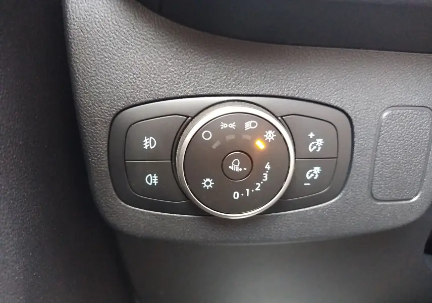 Gros plan sur la commande d'éclairage avec réglage de la luminosité dans l'habitacle d'une Ford Puma blanche.