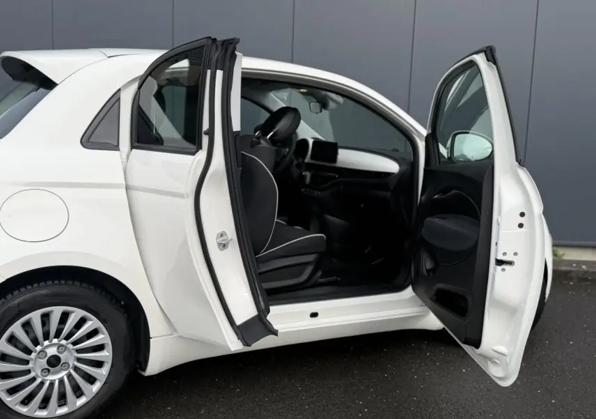 Fiat 500 électrique blanche vue 3/4 avant droit, avec calandre épurée et jantes multibranches.