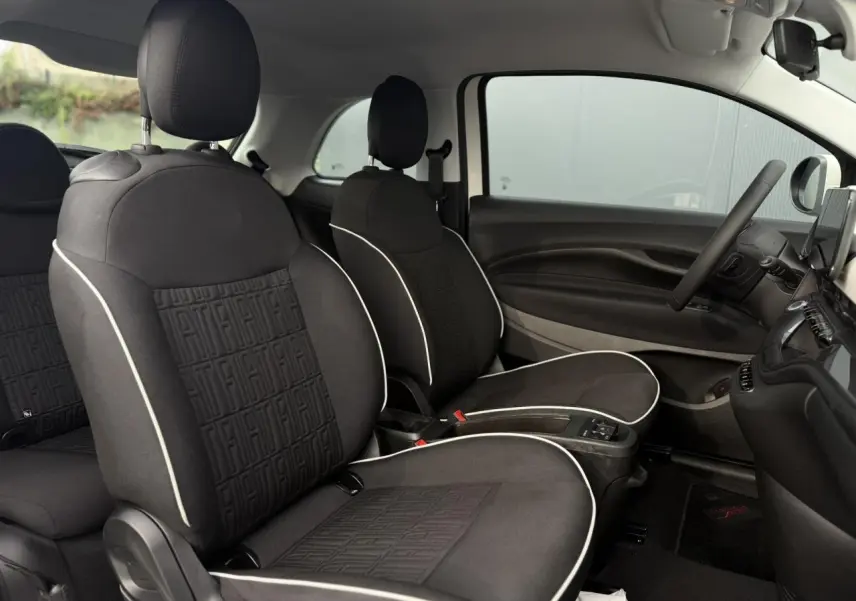 Gros plan sur l'avant droit blanc de la FIAT 500 électrique, mettant en valeur le phare rond et la jante alu stylisée.