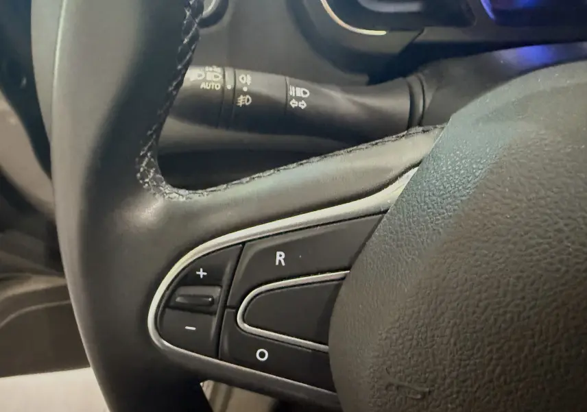 Gros plan sur les commandes de régulateur de vitesse au volant cuir noir du Renault Grand Scenic IV Business gris Cassiopée.