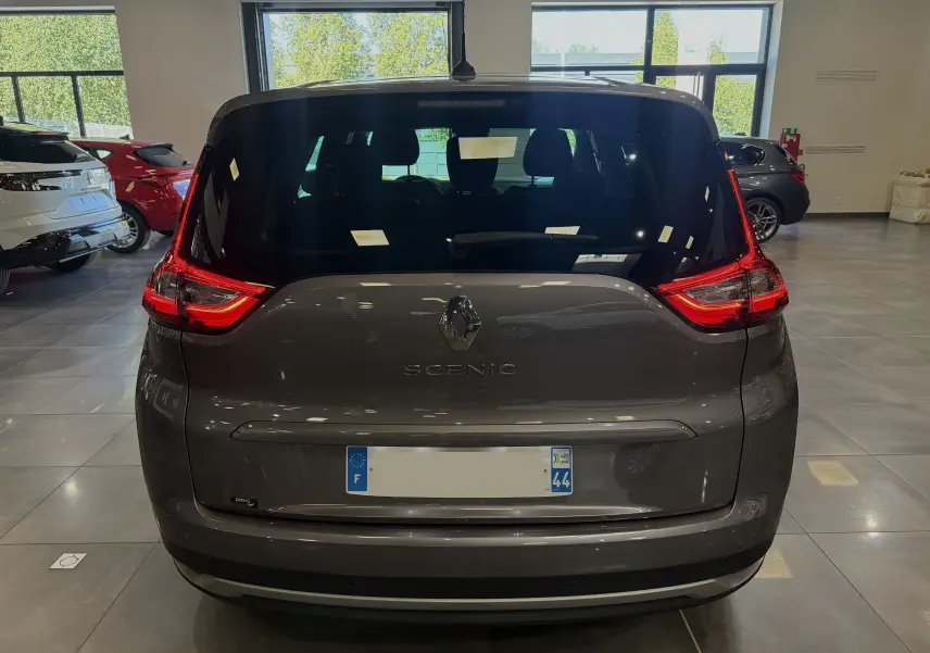 Vue arrière du Renault Grand Scenic IV Business gris Cassiopée avec feux LED et logo Renault bien visibles en intérieur showroom.