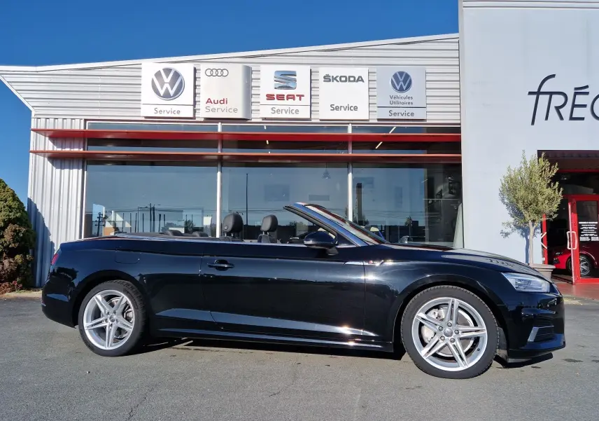 Audi A5 Cabriolet noir vue de profil côté gauche, capote ouverte, jantes alliage cinq branches visibles.