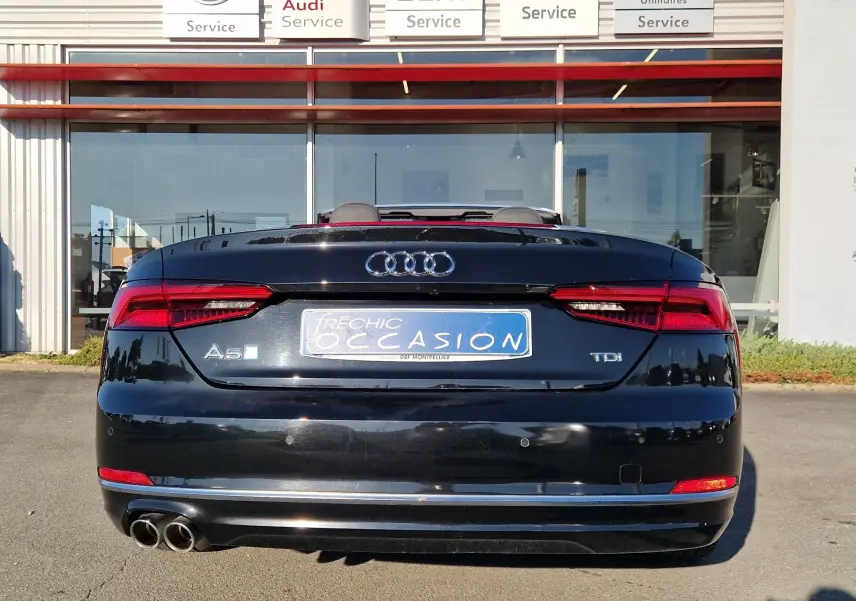 Vue arrière d'une Audi A5 Cabriolet noire de 2017 avec double sortie d'échappement et feux LED allumés.