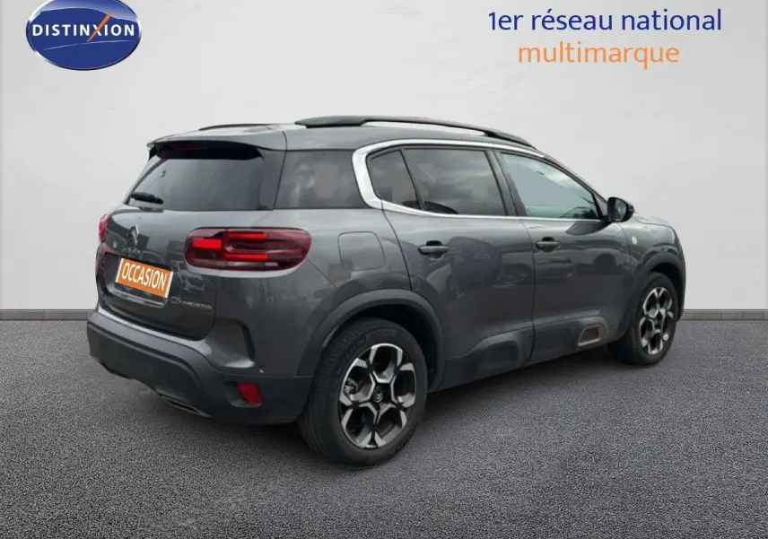 Vue 3/4 arrière droite d’un Citroën C5 Aircross gris platinium avec jantes bi-ton et vitres teintées.