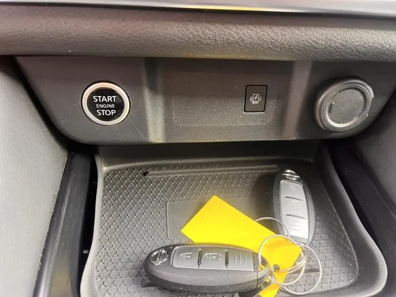Gros plan sur la console centrale du Nissan Qashqai 2022 avec bouton start/stop et clés posées sur un tapis antidérapant noir.