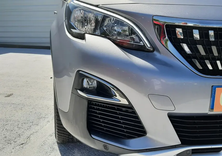 Vue de face côté gauche d'un Peugeot 3008 gris Artense mettant en valeur ses phares et sa calandre chromée.