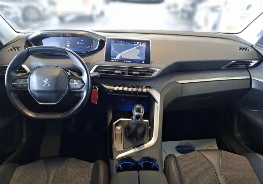 Vue intérieure du tableau de bord et volant du Peugeot 3008 gris, avec écran tactile et levier de vitesse manuel.