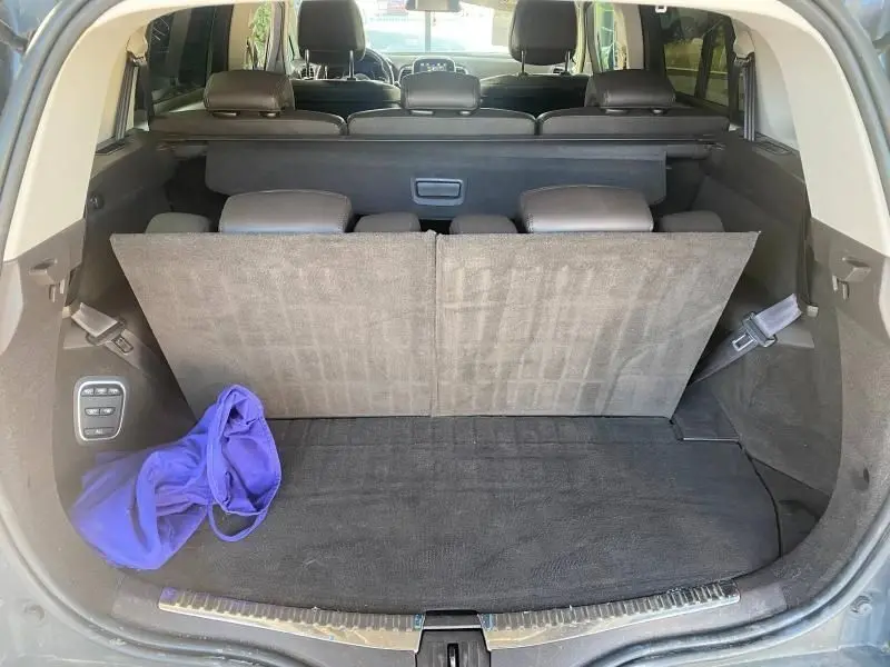 Vue arrière du coffre ouvert d'un Renault Espace V gris, montrant la troisième rangée de sièges relevée et un sac violet à gauche.