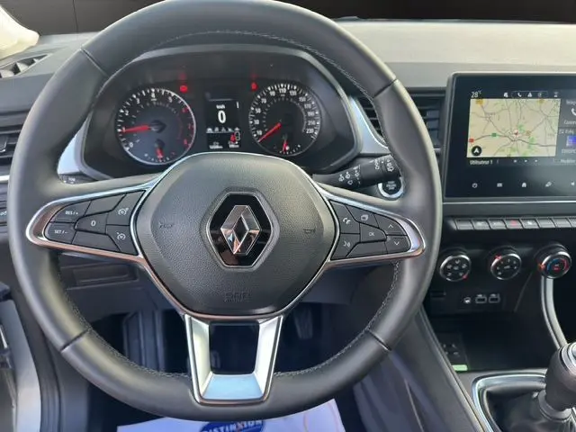 Vue intérieure centrée sur le volant cuir du Renault Captur TCe 90 Evolution 2024 avec tableau de bord et écran tactile visible.
