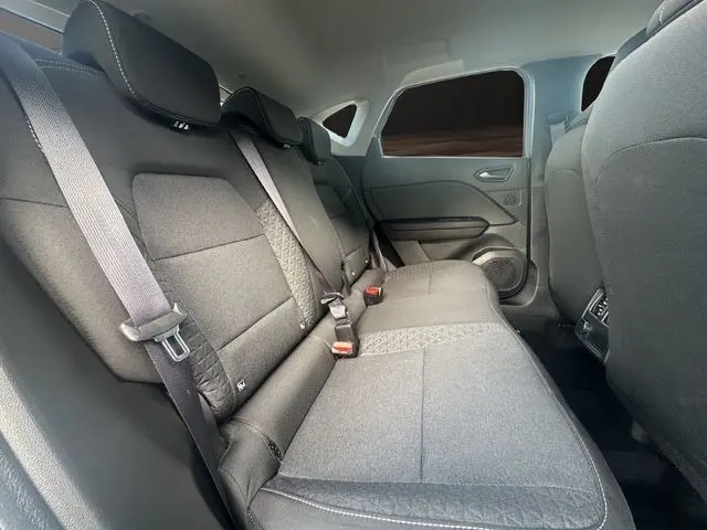Vue intérieure arrière du Renault Captur TCe 90 Evolution 2024, sièges tissu noir avec ceinture de sécurité et porte côté droit.