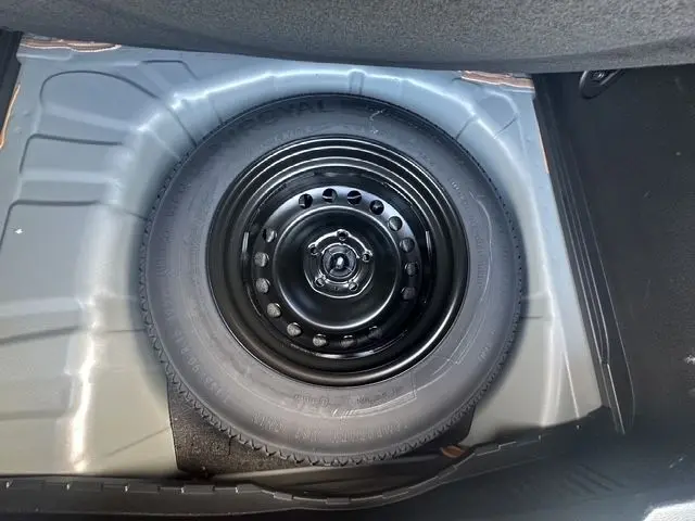 Roue de secours noire en gros plan dans le coffre d'un Renault Captur gris Highland 2024.