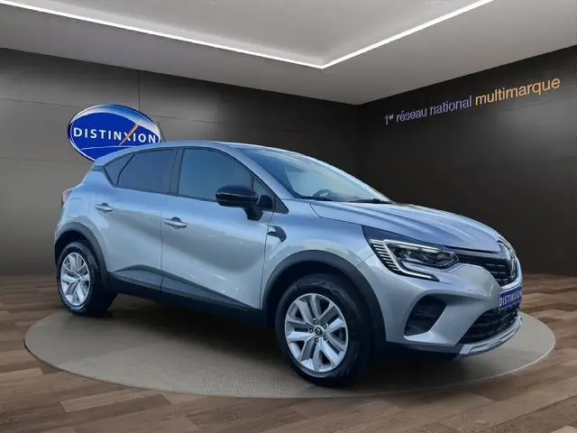 Renault Captur TCE 90 Evolution gris Highland en 3/4 avant droit, avec jantes alliage et calandre noire brillante.