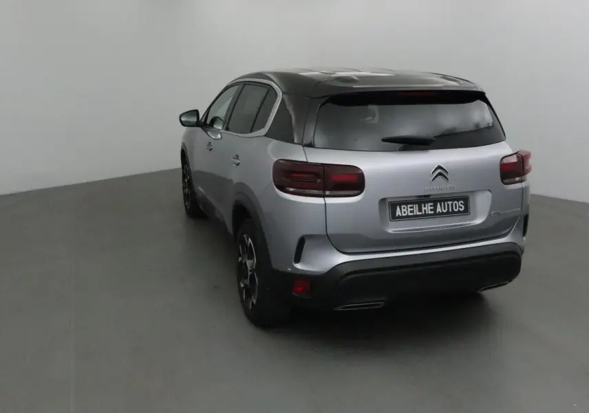 Vue 3/4 arrière droite du Citroën C5 Aircross gris Artense avec toit noir et feux arrière LED dans un studio.