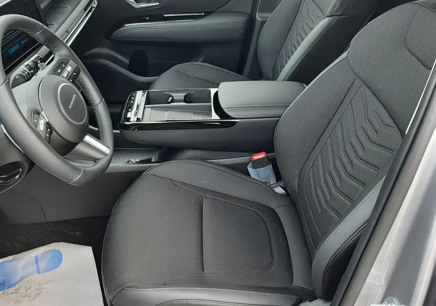 Vue intérieure côté conducteur du Hyundai Tucson 2025 gris Ecotronic, sièges noirs tissu et cuir avec console centrale élégante.