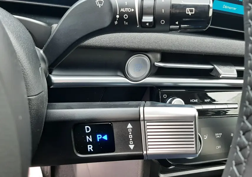 Détail intérieur du Hyundai Tucson 2025 montrant la commande de boîte automatique et le bouton start/stop sur tableau de bord noir.