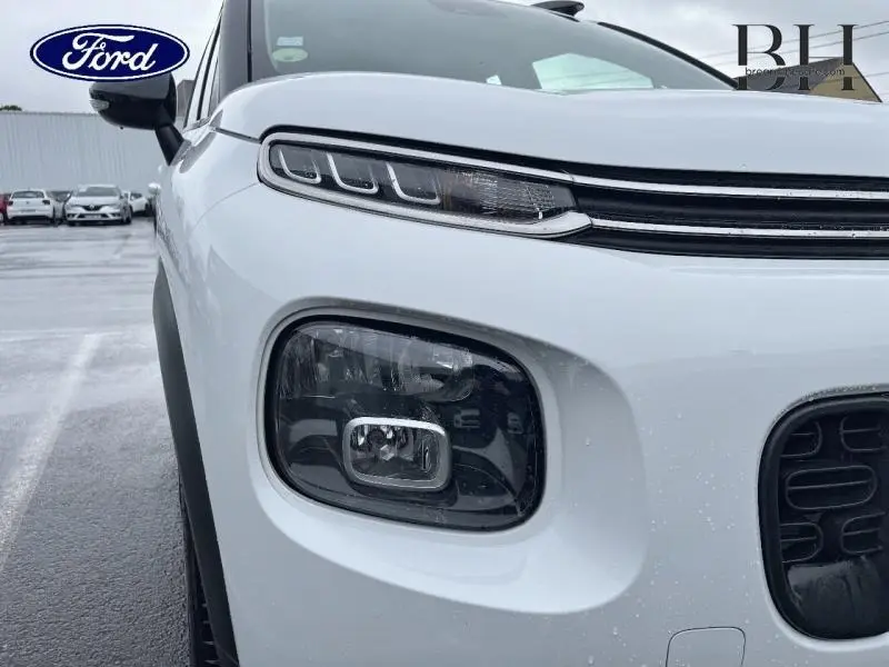 Gros plan sur l'avant gauche blanc naturel d'une Citroën C3 Aircross 2019 avec phares distinctifs et calandre noire.