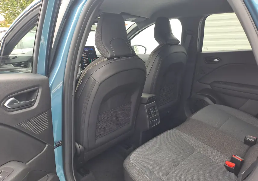 Vue intérieure arrière côté gauche du Renault SYMBIOZ bleu Mercure, montrant les sièges avant en cuir noir et banquette tissu gris.