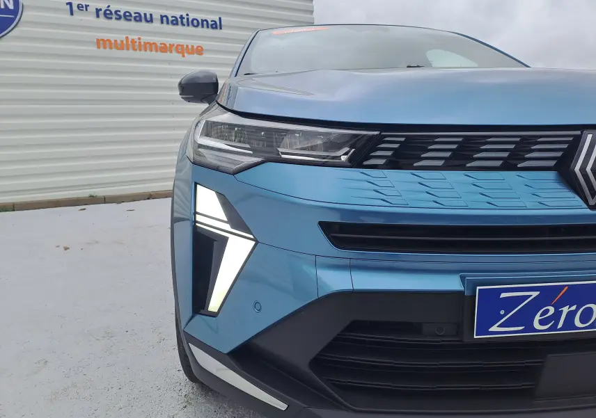 Vue avant gauche rapprochée d'une Renault Symbioz bleu mercure avec feux LED distinctifs allumés.