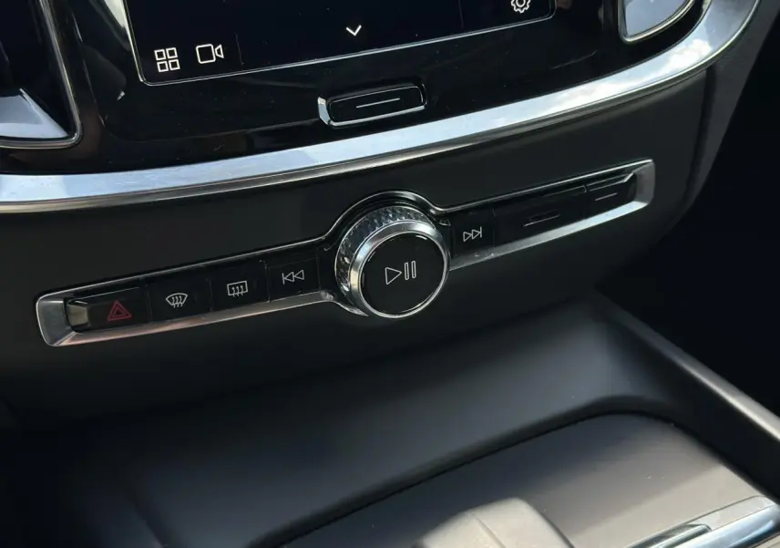 Bouton central de contrôle multimédia et commandes audio sur la console d'une Volvo S60 rouge Fusion 2024.