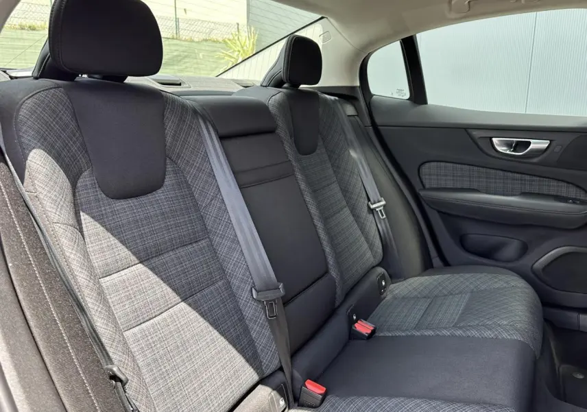 Vue intérieure de la banquette arrière grise à motifs de la Volvo S60 2024, côté droit avec ceinture de sécurité visible.