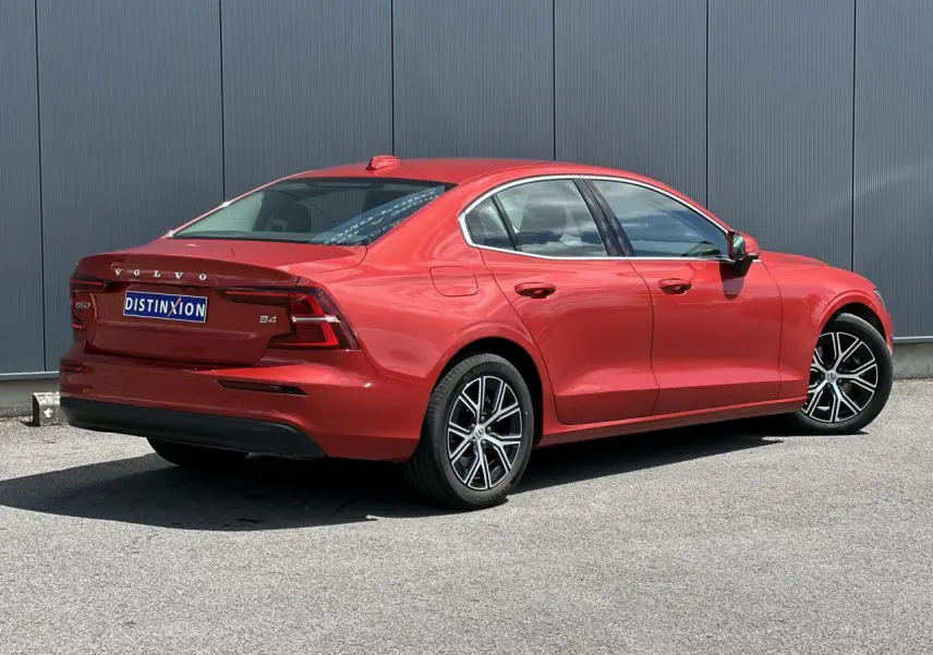 Vue 3/4 arrière droite d'une Volvo S60 B4 rouge Fusion avec jantes alliage 17 pouces et contours de fenêtres chromés.