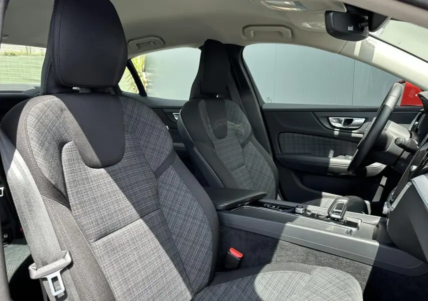 Intérieur avant de la Volvo S60 B4 2024, sièges tissu gris à motif carreaux, console centrale et volant visibles côté droit.