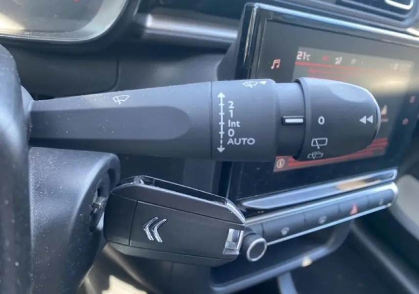 Gros plan sur la commande d'essuie-glace et la clé noire avec logo Citroën dans l'habitacle du C3 gris Artense.