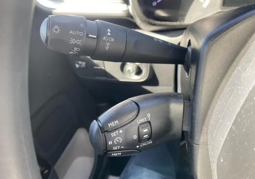 Gros plan sur les commandes de régulateur de vitesse et éclairage du tableau de bord d'une Citroën C3 gris Artense 2022.