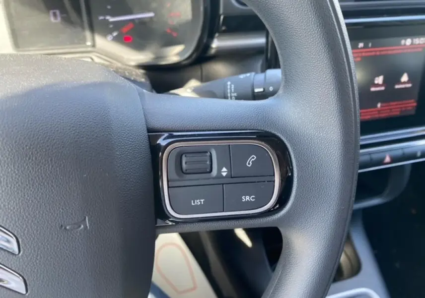 Gros plan sur les commandes du volant du Citroën C3 1.2 83 Shine 2022, intérieur noir avec écran tactile visible.